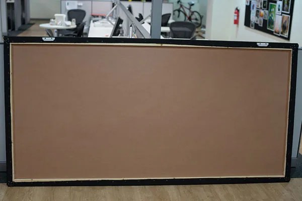 The back of a 4 by 8 ft CinemaBoard: a hardboard back panel inside a solid wood perimeter frame, with two white cleat blocks fitted at the top edge