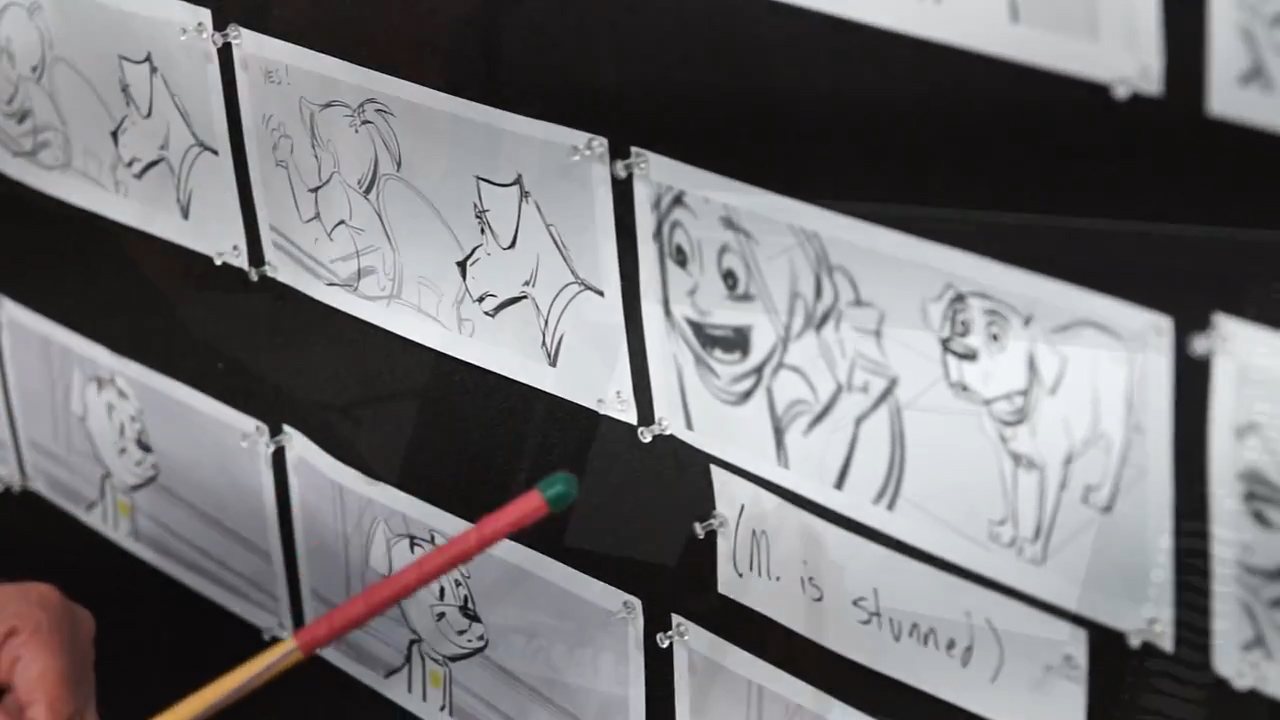 Close view of hand-drawn storyboard sheets pinned in rows to the black fabric face of a CinemaBoard, pins at the corners, a pencil in the foreground